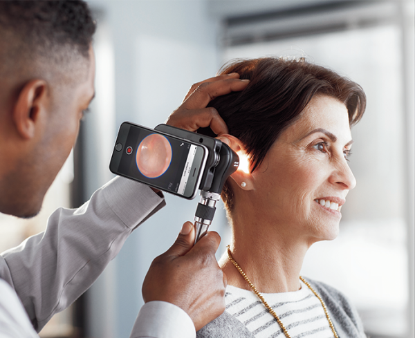 Healthcare professional using a medical device to look into a patient's ear